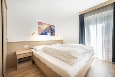 a white bed in a room with a window at Pivan Apartments in Selva di Val Gardena
