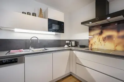 a kitchen with white cabinets and a sink at Pivan Apartments in Selva di Val Gardena