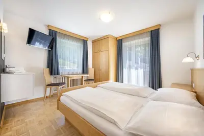 a bedroom with a large white bed and a desk at Pivan Apartments in Selva di Val Gardena