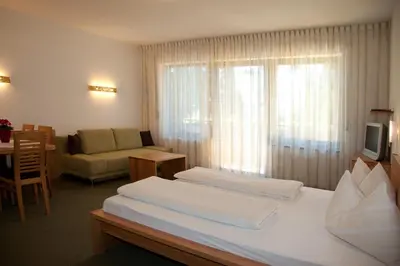 a hotel room with two beds and a couch at Living Apartments Morgenstern in Merano
