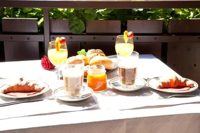 a table with plates of food and glasses of drinks at Living Apartments Morgenstern in Merano