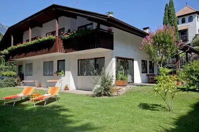 a house with chairs and a balcony on a yard at Living Apartments Morgenstern in Merano