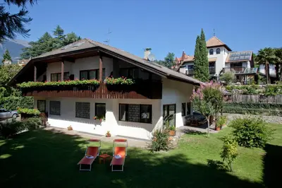 a house with two chairs in the yard at Living Apartments Morgenstern in Merano