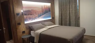 a bedroom with a bed and a window with a picture at Chalet Radola in Campitello di Fassa