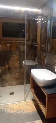 a bathroom with a sink and a glass shower at Chalet Radola in Campitello di Fassa