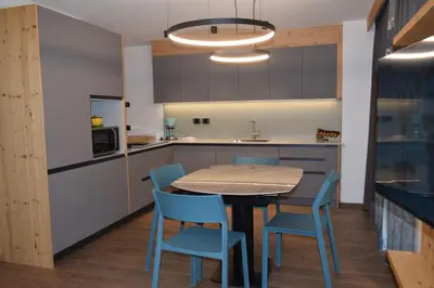 a kitchen with a table and blue chairs at Chalet Radola in Campitello di Fassa