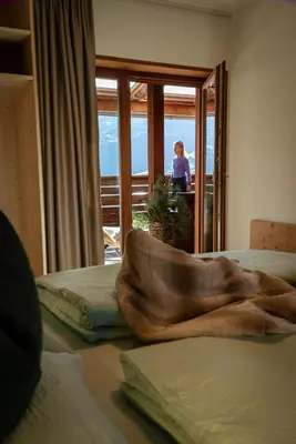 a bedroom with two beds and a woman looking out the window at LA FUNDNEYT art & guesthouse in Laion