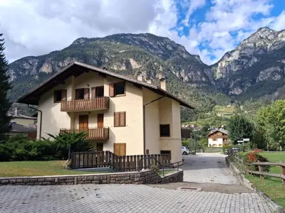 a house with a balcony and mountains in the background at Casa Tullia by Go New Location in Ziano di Fiemme