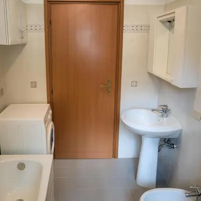 a bathroom with a toilet sink and a wooden door at Casa Tullia by Go New Location in Ziano di Fiemme