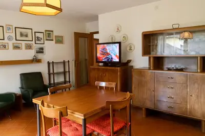 a dining room with a wooden table and a television at Casa Tullia by Go New Location in Ziano di Fiemme