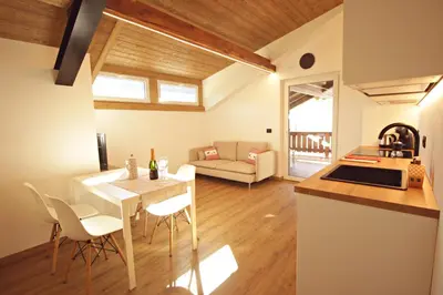 a kitchen and living room with a table and chairs at Guest House Dezulian in Castello di Fiemme