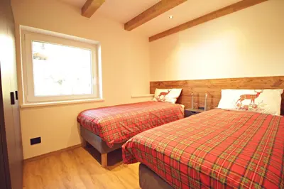 a bedroom with two beds and a window at Guest House Dezulian in Castello di Fiemme