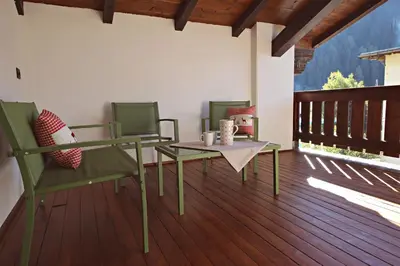 a patio with chairs and a table and a table and chairs at Guest House Dezulian in Castello di Fiemme
