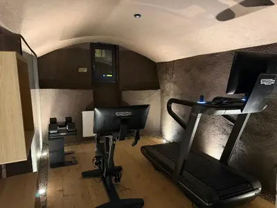 a room with a gym with a treadmill and a desk at La Maison 35 - Bruneck - zentral gelegene Appartments in Brunico