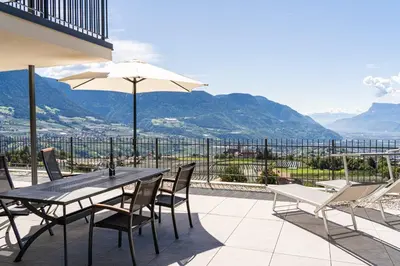 a patio with a table and chairs and an umbrella at Appartements Laimer in Haslach in Tirolo