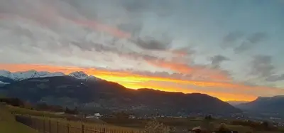 a sunset over a mountain range with a fence at Appartements Laimer in Haslach in Tirolo
