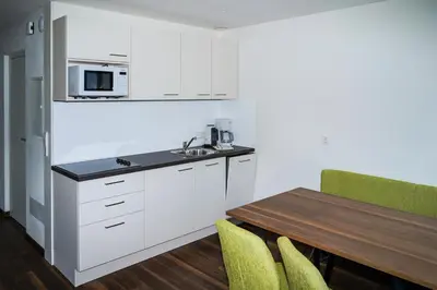 a kitchen with white cabinets and a wooden table at Appartements Laimer in Haslach in Tirolo