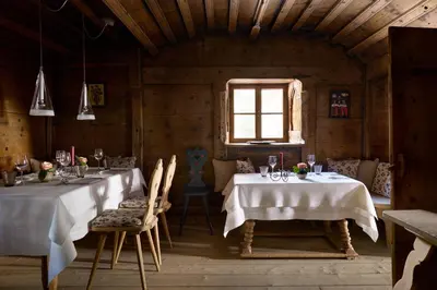 a dining room with two tables and a window at Berghoferin Fine Hotel & Hideaway in Redagno