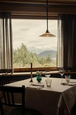 a table with a candle and wine glasses in front of a window at Berghoferin Fine Hotel & Hideaway in Redagno