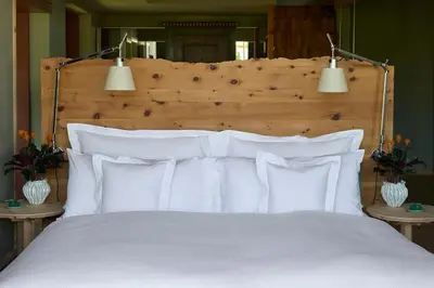 a bed with white pillows and two lights above it at Berghoferin Fine Hotel & Hideaway in Redagno
