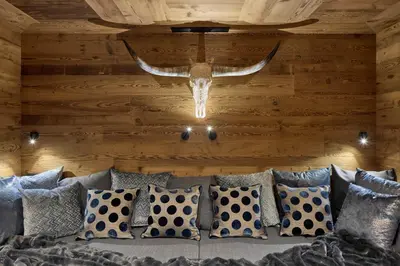 a chandelier hanging from a ceiling with a couch with pillows at Chalet Altera by Elite Villas in Ortisei