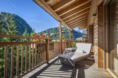 a deck with a bench and a view of the mountains at Mayr Natur Apartments in Santa Cristina in Val Gardena