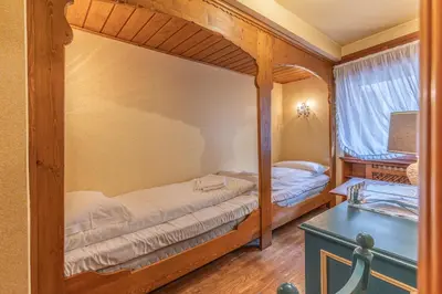 a bedroom with two bunk beds and a table at Casa Bigontina 19, in the center of Cortina in Cortina dʼAmpezzo