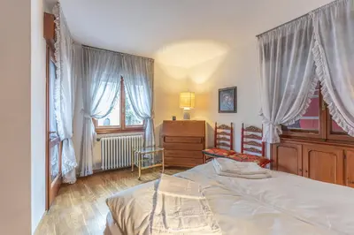 a bedroom with a bed and a dresser and windows at Casa Bigontina 19, in the center of Cortina in Cortina dʼAmpezzo