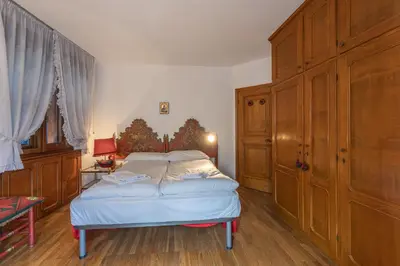 a bedroom with a bed and a wooden cabinet at Casa Bigontina 19, in the center of Cortina in Cortina dʼAmpezzo