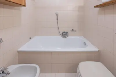 a bathroom with a tub and a toilet and a sink at Casa De Zeto, con balcone e vicina al centro in Cortina dʼAmpezzo