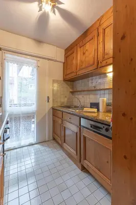 a kitchen with wooden cabinets and a tile floor at Casa De Zeto, con balcone e vicina al centro in Cortina dʼAmpezzo