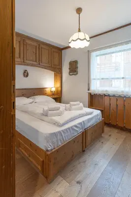 a bedroom with a large bed with a wooden frame at Casa De Zeto, con balcone e vicina al centro in Cortina dʼAmpezzo