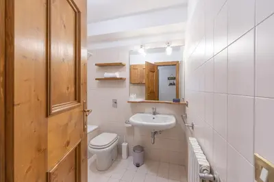a white bathroom with a toilet and a sink at Casa De Zeto, con balcone e vicina al centro in Cortina dʼAmpezzo