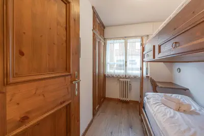 a small bedroom with a bed and a wooden cabinet at Casa De Zeto, con balcone e vicina al centro in Cortina dʼAmpezzo