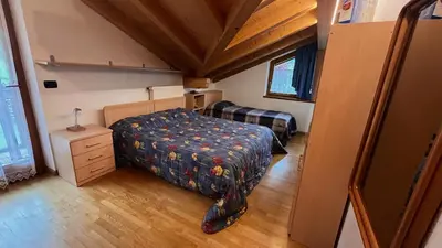 a bedroom with a bed and a dresser in a room at Lauton Dolomiti Relax Apartment - mit Jacuzzi-Badewanne in Ziano di Fiemme