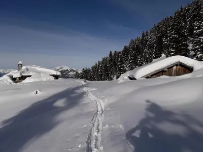 a snow covered house with tracks in the snow at Lauton Dolomiti Relax Apartment - mit Jacuzzi-Badewanne in Ziano di Fiemme
