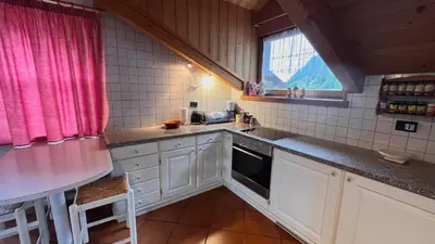 a kitchen with white cabinets and a sink and a window at Lauton Dolomiti Relax Apartment - mit Jacuzzi-Badewanne in Ziano di Fiemme