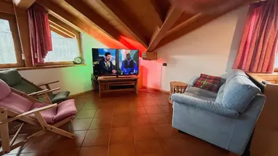 a living room with chairs and a flat screen tv at Lauton Dolomiti Relax Apartment - mit Jacuzzi-Badewanne in Ziano di Fiemme