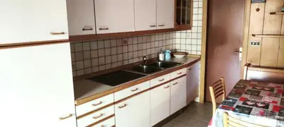 a kitchen with a sink and white cabinets and a table at Casa Checolongo by Sunhome Fiemme in Ziano di Fiemme