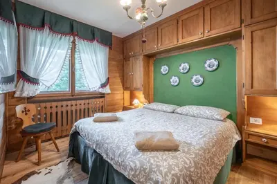 a bedroom with a bed and a green wall at Appartamento 5 Torri - Dolce Vita Stay in Cortina dʼAmpezzo