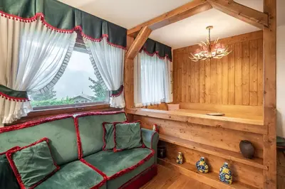 a living room with a green couch and a window at Appartamento 5 Torri - Dolce Vita Stay in Cortina dʼAmpezzo