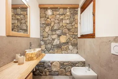 a stone bathroom with a tub and a sink at Appartamento 5 Torri - Dolce Vita Stay in Cortina dʼAmpezzo