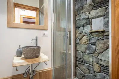 a bathroom with a sink and a stone wall at Appartamento 5 Torri - Dolce Vita Stay in Cortina dʼAmpezzo