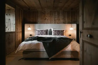 a bedroom with a large bed with wooden walls at Historic Alpine Lodge In The Heart Of South Tyrol in Villandro