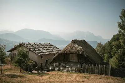 an old house with a fence and mountains in the background at Historic Alpine Lodge In The Heart Of South Tyrol in Villandro