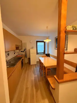 a kitchen with a wooden table and a dining room at Appartamento Moena in Moena