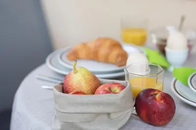 a table with a basket of apples and a glass of orange juice at Appartement Huber in Merano