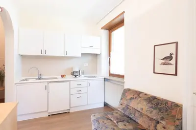 a kitchen with white cabinets and a bird on the wall at Appartement Huber in Merano