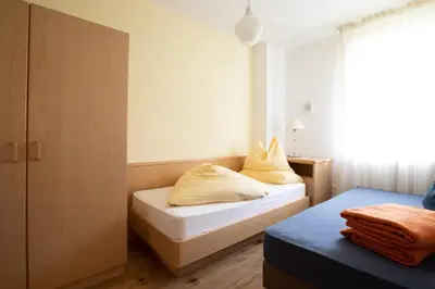 a small room with two beds and a window at Appartement Huber in Merano