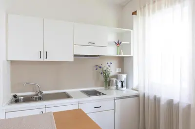 a kitchen with white cabinets and a sink and a window at Appartement Huber in Merano